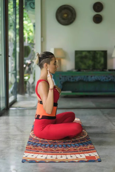 Красивая молодая женщина упражнениями йоги в позе лотоса с руку на сердце дома, вид сбоку — стоковое фото